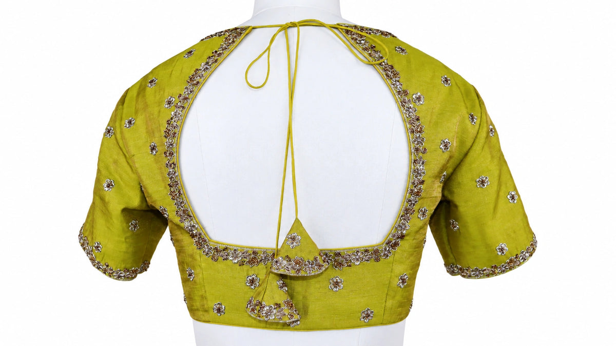 Turquoise florals, fresh green and bright pink bring a vivid contrast to this three-piece lehenga set by Vinisha Rao Designer Studio. The gathered Gaji silk lehenga features multicoloured floral motifs and a broad pink patterned border. The green raw silk blouse has a front button fastening, elbow-length sleeves and metallic floral embroidery around the neckline and cuffs. An open back with tassel ties completes the blouse, while the pink chiffon dupatta adds a soft layer with an embellished scalloped borde