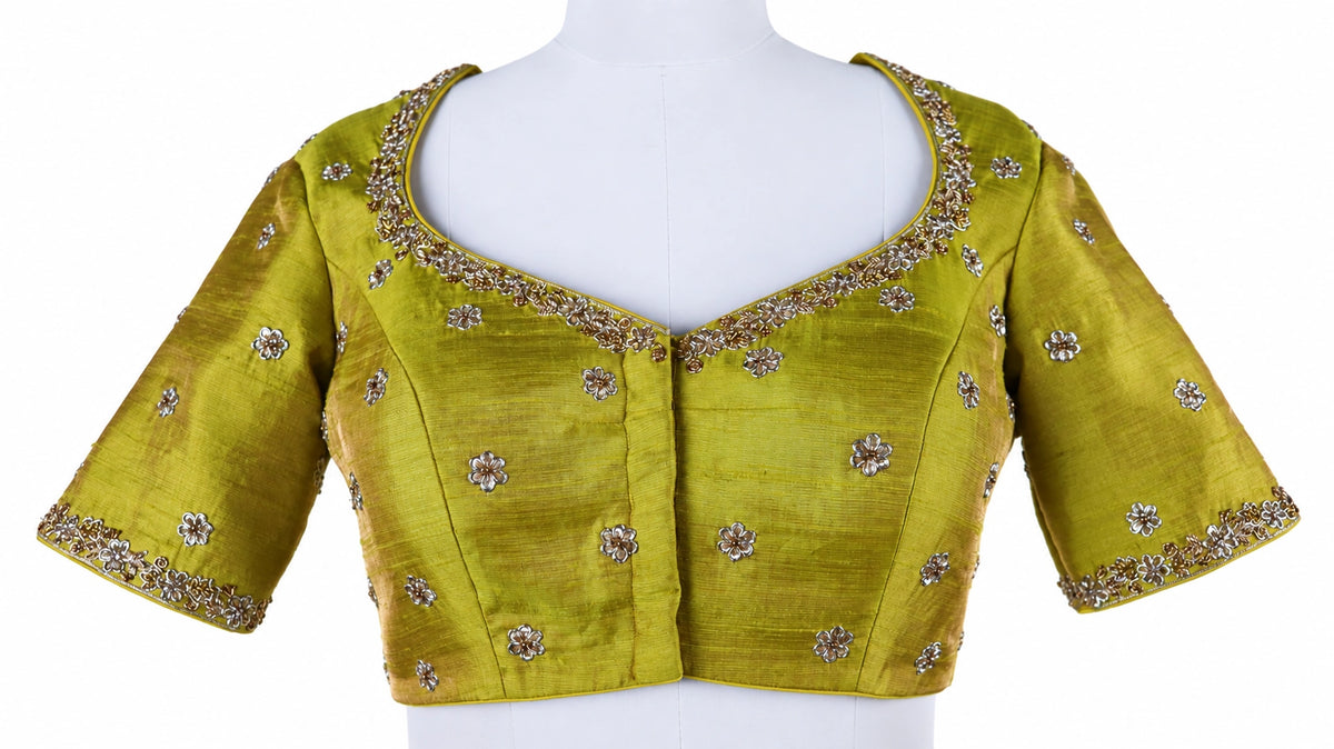 Turquoise florals, fresh green and bright pink bring a vivid contrast to this three-piece lehenga set by Vinisha Rao Designer Studio. The gathered Gaji silk lehenga features multicoloured floral motifs and a broad pink patterned border. The green raw silk blouse has a front button fastening, elbow-length sleeves and metallic floral embroidery around the neckline and cuffs. An open back with tassel ties completes the blouse, while the pink chiffon dupatta adds a soft layer with an embellished scalloped borde